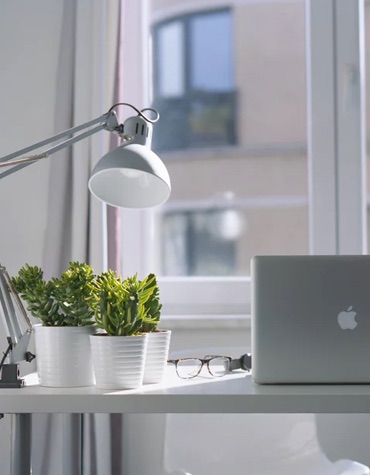 A desk holding various objects including glasses and laptop
